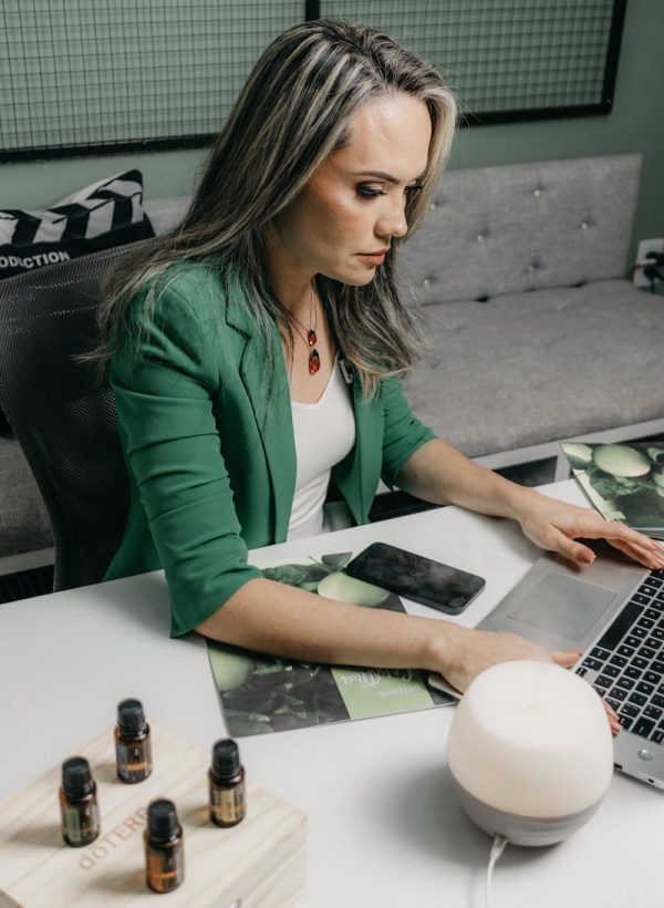 Businesswoman in green blazer focused on work with laptop at office desk.